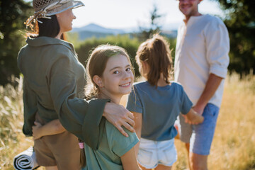 Wall Mural - Happy young parents with daughters walking for picnic in nature in summer day,