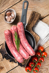 Wall Mural - Raw sausages ready for cooking in a skillet, uncooked meat. Wooden background. Top view