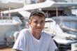 Portrait of a handsome teenager in a baseball cap posing with yachts.