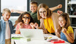 © JenkoAtaman - Teacher and cheerful  schoolkids   looking at laptop screen and celebrate   successful completion of collective school work   during online lesson