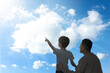 Godparent with child pointing at blue sky with white clouds