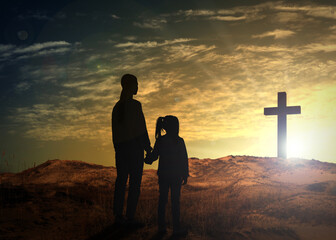 Silhouettes of godparent with child in field at sunrise