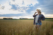 © olga_sova - A beautiful middle-aged farmer woman in a straw hat and a plaid shirt stands in a field of golden ripening wheat during the daytime in the sunlight