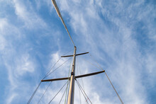 Mast Of Sailing Yacht With Ropes Without Sail At Blue Sky Background. View From Below Mast Boat Against Sky With Cumulus Clouds In Sea. Transportation, Cruise, Sailing, Yachting Concept. Copy Space