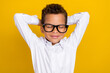© deagreez - Portrait of cute dreamy boy stylish white clothes glasses hold hand behind head relax after school week isolated on yellow color background