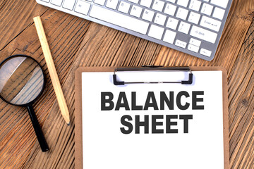 Poster - BALANCE SHEET text on paper clipboard with magnifier and keyboard on wooden background