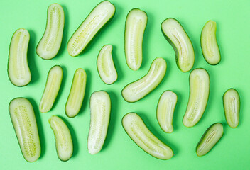 Wall Mural - Cut cucumbers on green paper. Top view.