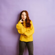 © contrastwerkstatt - thoughtful redhead woman looks irritated to the side, copyspace with purple background