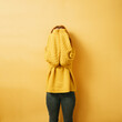 © contrastwerkstatt - redhead woman hiding her face behind her arms, copyspace against yellow background
