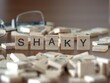 shaky word or concept represented by wooden letter tiles on a wooden table with glasses and a book