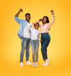 © Prostock-studio - Victory concept. Excited african american family shaking clenched fists, making winner gesture, yellow background