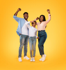 Wall Mural - Victory concept. Excited african american family shaking clenched fists, making winner gesture, yellow background