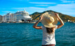 Woman with hat looking at sea and cruise boat