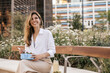 © Look! - Smiling young caucasian business woman is sitting on bench outside and eating salad. Blonde smiles with her teeth, wears shirt. Free time concept