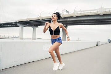 Wall Mural - Millennial runner woman running sports training in the city. Fitness tracker on the arm.