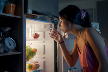 Thirsty Woman Looking In The Fridge At Night