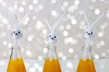 Wall Mural - Orange drink decorated with white rabbit on light background for children party.