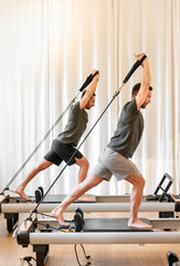 sportsmen exercising on pilates reformer beds