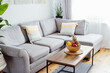 © okrasiuk - Stylish and modern scandinavian interior of open space living room with bamboo bowl with fruits on the coffee table, gray couch sofa, and many green plants. Biophilia. Open space home interior design