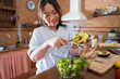 © ADDICTIVE STOCK - Asian female adding avocado to salad