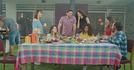 Family meeting at backyard barbecue party. BBQ table. Diverse friends gathered together for celebration. Summer holidays