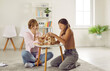 © Studio Romantic - Adolescent child and professional therapist having fun during therapy session. Happy teenage girl sitting on floor in cozy room and playing board game together with psychotherapist or psychologist