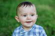 Portrait of little smiling boy in park. Close-up. Toddler boy walks in park. Brown eyes.