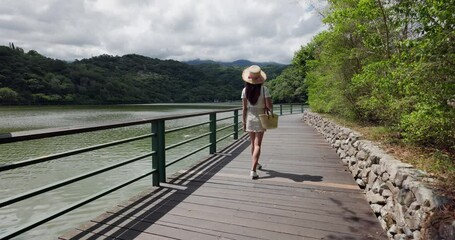 Wall Mural - Woman walk at the wooden pathway at lakeside