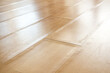 © Petra Richli - Swollen laminate flooring from flood or water damage, perspective view. Close up of light beige buckling laminate boards with bent edge pieces. Floor damage texture. Selective focus in center.