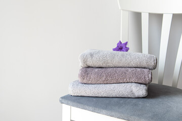 Stack of gray towels and flower on chair. Space for text. Towels washed and folded