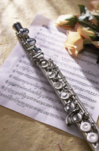 Close-up Of A Flute On Music Sheets Near Roses