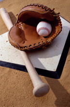 Baseball Bat With A Glove And A Baseball On The Home Base