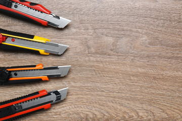 Canvas Print - Many different utility knives on wooden table, flat lay. Space for text