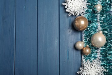 bright tinsel and christmas decor on light blue wooden background, flat lay. space for text