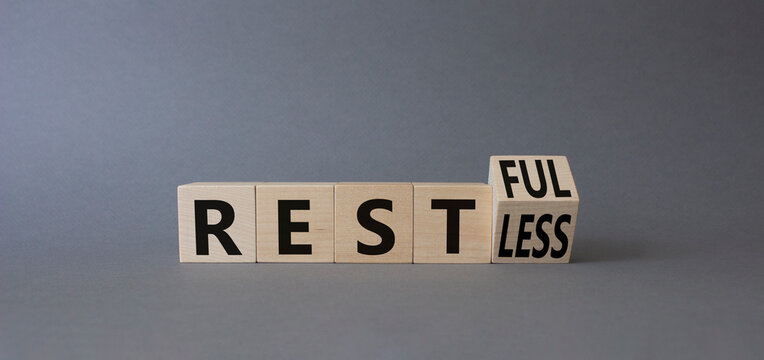 Restful and Restless symbol. Turned wooden cubes with words Restless and Restful. Beautiful grey background. Business concept. Copy space