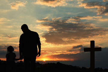 Wall Mural - Silhouettes of godparent with child in field at sunset
