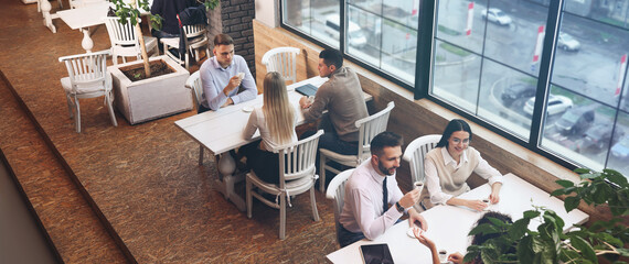 Sticker - Coworkers having coffee break near window in cafe, above view. Banner design