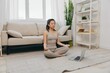 © SHOTPRIME STUDIO - Asian woman in tracksuit sits with laptop in lotus position at home and meditates with eyes closed with a slight smile, mental health support lifestyle