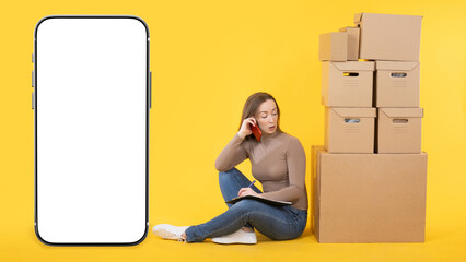 Poster - Woman small business owner. Phone blank screen. Girl is sitting in front of boxes. Smartphone mockup. Businesswoman is talking on phone. Big phone on yellow. Place for your proposal on white