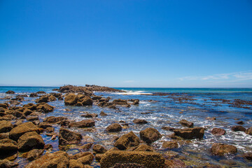 a gorgeous summer landscape at the beach with vast deep blue ocean water and large rocks along the shore with waves rolling over the rocks at Royal Beach park on White Point Beach in San Pedro