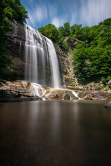  waterfall long exposure, suuctu waterfall in forest spring time with blurred water flow and clouds on top