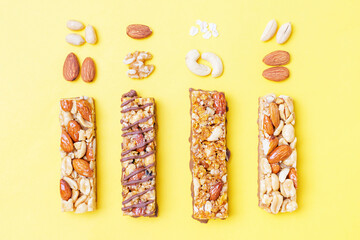 Protein bars and nuts on yellow background top view close-up.