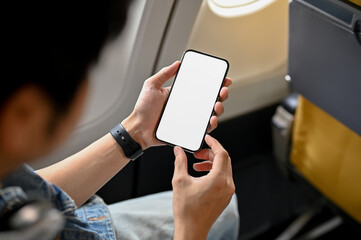 Wall Mural - Male passenger using his smartphone during the flight. phone white screen mockup.