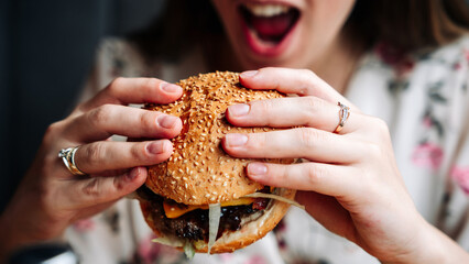 Woman hamburger eat. Hungry Caucasian Female Eating Tasty Burger. Fast food, people and unhealthy eating concept.