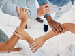 © Emily N/peopleimages.com - Hands, teamwork and collaboration with a team of business people holding arms in a huddle or pentagon from above. Trust, support or motivation of group at work or office in solidarity, unity or union