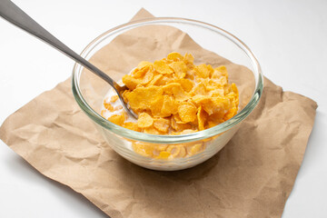 Wall Mural - Healthy food concept, Cornflakes and milk with spoon in bowl on brown paper for breakfast meal