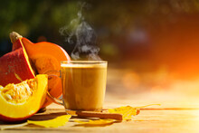 Pumpkin Latte Coffee With Spices And Cinnamon. Autumn Hot Drink On A Rustic Wooden Table Decorated With Yellow Leaves And Pumpkin Under The Sun. Cosiness, Halloween, Warmth Concept. 