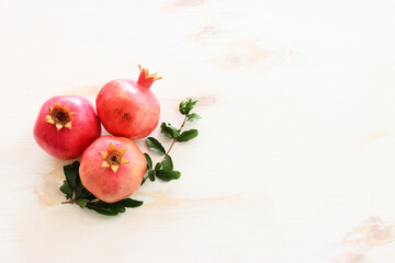 Rosh hashanah (jewish New Year holiday) concept. Pomegranate traditional symbol over wooden white background