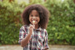 © Thanumporn - Happy African-American kid girl with a lollipop in her hands in the garden or outdoors.