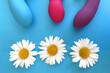 Sex shop assortment. Three vibrators and chamomile on blue background. Sex toy for enjoyment
